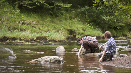 Two brothers skipping stones at small river in the brecon beacons