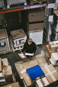 High angle view of businesswoman examining packages at distribution warehouse