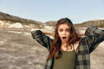 Portrait of young woman standing against sky