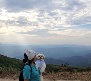 Man with dog on mountain against sky