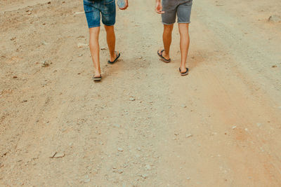 Low section of people walking on beach