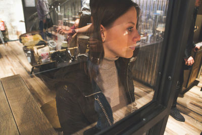 Portrait of young woman sitting on table in restaurant