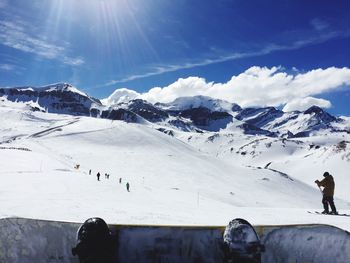 People on snowcapped mountains against blue sky