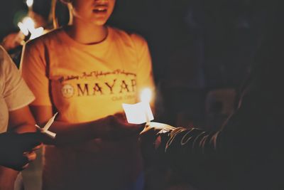 Midsection of man holding lit candles