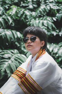 Woman wearing sunglasses while sitting against plants