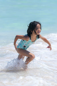 Girl looking away while running in sea