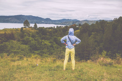 Rear view of man photographing on field against sky