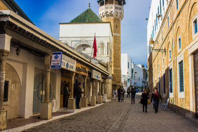 People walking on footpath amidst buildings in city