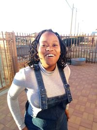 Portrait of smiling young woman standing against built structure