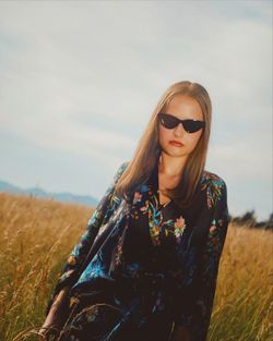 Young woman wearing sunglasses on field against sky