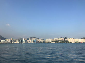 Sea by buildings against blue sky