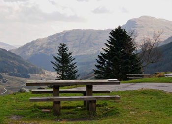 Empty bench on table against mountains