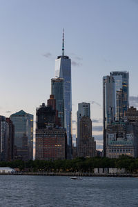 Lower manhattan skyline at sunset viewed from the water.