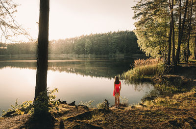 Rear view of woman standing on lakeshore