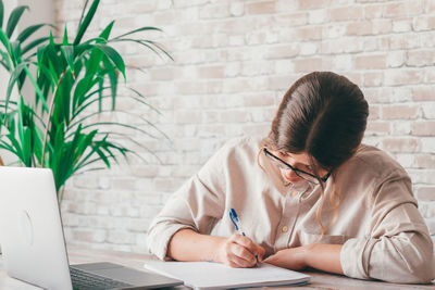 Side view of woman using laptop at home