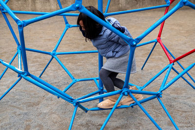 Kid playing climbing globe, metal dome climber in outdoor playground.