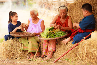 Senior women with kids sitting on hay