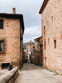 Alley amidst buildings in town against sky