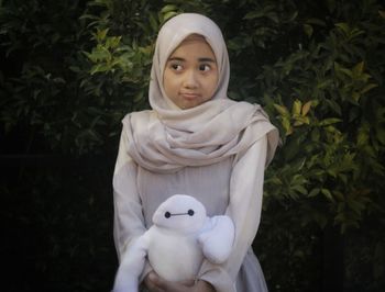 Young woman wearing hijab holding toy