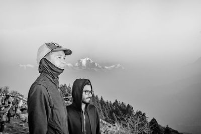 Friends in hood clothing standing against sky