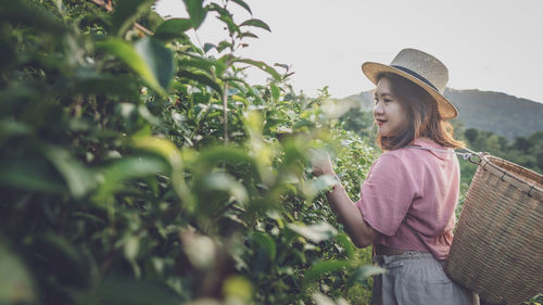 Woman carrying basket standing by plants