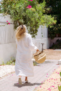 Woman wearing white dress running towards her house