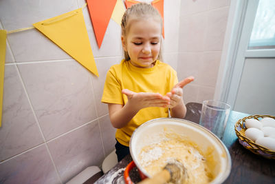 Girl kneads the dough for the easter holiday, white eggs on the table, burning candles