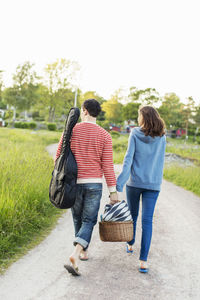 Full length rear view of couple walking on footpath in park