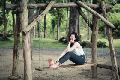 Portrait of smiling young woman sitting on wood