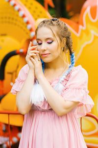 Sensual caucasian young woman with blue pigtails with bright makeup in an amusement park