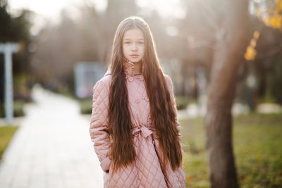 Portrait of young woman standing against trees