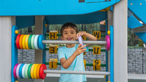 Full length of boy holding colorful standing against blue wall