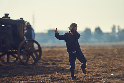 Boy dancing on dirt field