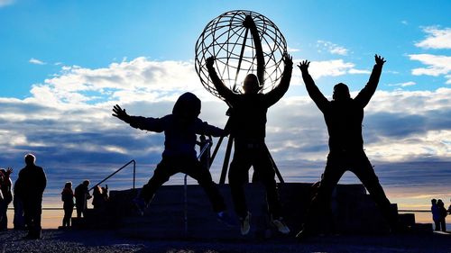 Silhouette people with ball in background at sunset