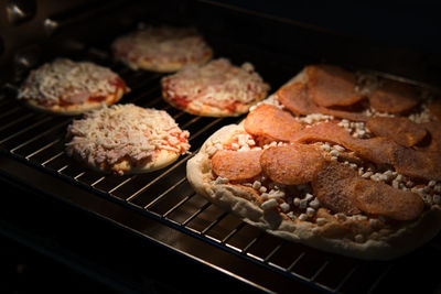 Frozen pizza semi-finished product with tomato sause and cheese on grill prepared for baking in oven