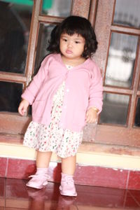 Full length of cute girl looking away while sitting on staircase