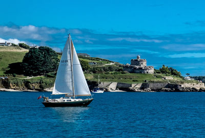 Sailboat sailing on sea against blue sky