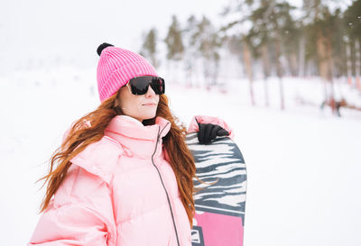 Portrait of smiling young woman standing against trees during winter