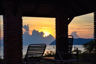 Silhouette chairs against orange sky during sunset