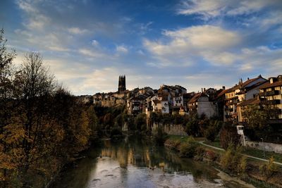 Scenic view of river by buildings in town against sky