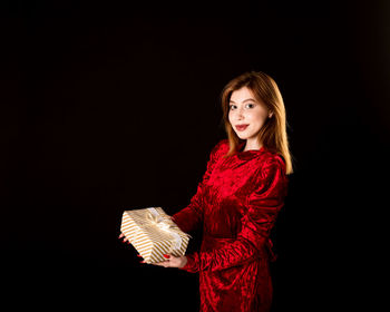 Portrait of a smiling young woman against black background