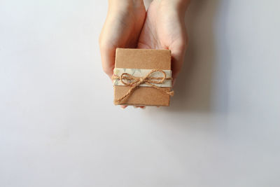 Cropped hand of woman holding gift box against white background