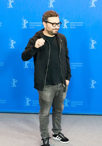 Young man standing against blue wall