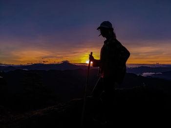 Silhouette man standing on mountain against sky during sunset