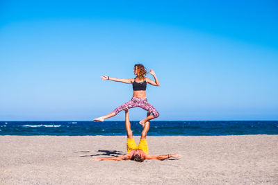 Couple exercising at beach on sunny day