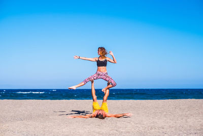 Woman with umbrella on beach against clear sky