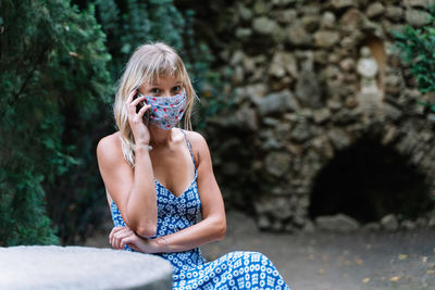 Woman with a mask sitting in a park talking to her mobile