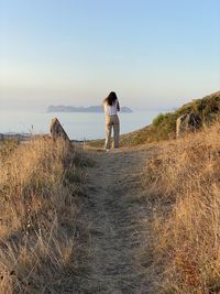 Rear view of woman standing on land against sky