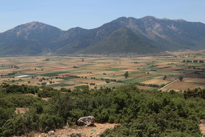 Scenic view of agricultural field by mountains against sky