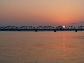 Bridge over river against sky during sunset